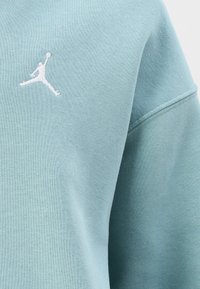 Mintgroene sweatshirt gemaakt van zachte stof, met een klein wit Jumpman-logo op de borst en subtiele stikdetails.