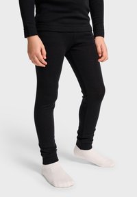 Svarta träningsleggings i mjukt, stretchigt tyg med en nära passform och ankellångt snitt; parat med vita, ankelhöga strumpor.