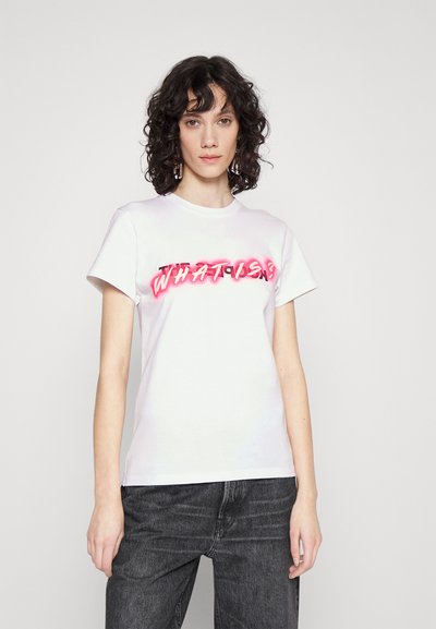 Witte katoenen t-shirt met een roze grafische print waarop de tekst "WAT IS?" staat in een vette, gestileerde lettertype. Korte mouwen en een ronde hals.