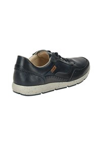 Zapatilla de cuero azul oscura con diseño perforado, suela moteada en gris, cordones y detalles de costura. Presenta un cuello acolchado para mayor comodidad.