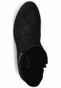 Bottine en suède noir avec un bout arrondi, design épuré, fermeture à glissière sur le côté et accent décoratif en métal.