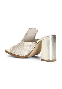 Mule aperto in pelle intrecciata con tacco a blocco metallico. La parte superiore presenta un motivo testurizzato e un bordo scallop. Colore: crema e oro.