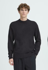 Maglione di colore grigio scuro, lavorato a maglia, con scollo rotondo, maniche lunghe e polsini e orlo a costine. Realizzato in tessuto morbido e testurizzato.