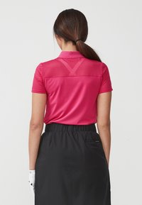 Rosa polo-skjorta med horisontella ränder och krage, ihopparad med en svart kjol med elastisk midja och en bakficka.