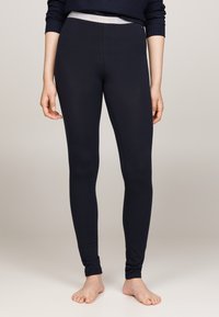 Marina leggings tillverkade av elastisk tyg, med en kontrasterande midja med varumärket i ljusgrått. Slät textur och åtsittande design.