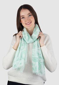 Lichtgroene sjaal van lichtgewicht stof, met paisleypatronen en franjes aan de randen, gedragen om de hals.