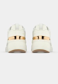 Paire de baskets blanches avec semelles épaisses et accents métalliques rose gold sur le talon, vues de dos sur un fond uni.
