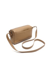 Piccola borsa a tracolla in pelle color cuoio con lunga tracolla regolabile e chiusura superiore a cerniera su uno sfondo bianco.