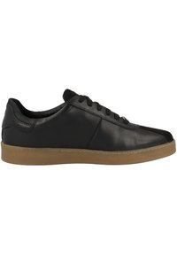Zapatilla de cuero negro con una superficie texturizada, suela de goma y suela de goma de contraste. Cuenta con punta redonda y diseño de cordones.