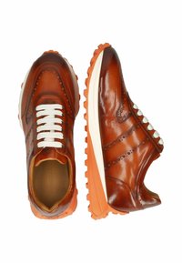 Zapatillas de piel marrón con cordones blancos, detalle perforado, suela media blanca y suela de goma naranja; punta redondeada y diseño elegante.