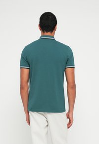 Türkizkék rövid ujjú galléros póló csíkos gallérral és egyszínű, texturált felülettel. Látható márkajelzés vagy további minták nélkül.