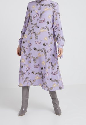 Lavendel midi-jurk met lange mouwen met bloemen- en bladdessin, knoopsluiting aan de voorkant, gecombineerd met glanzende grijze laarzen met hoge hakken.