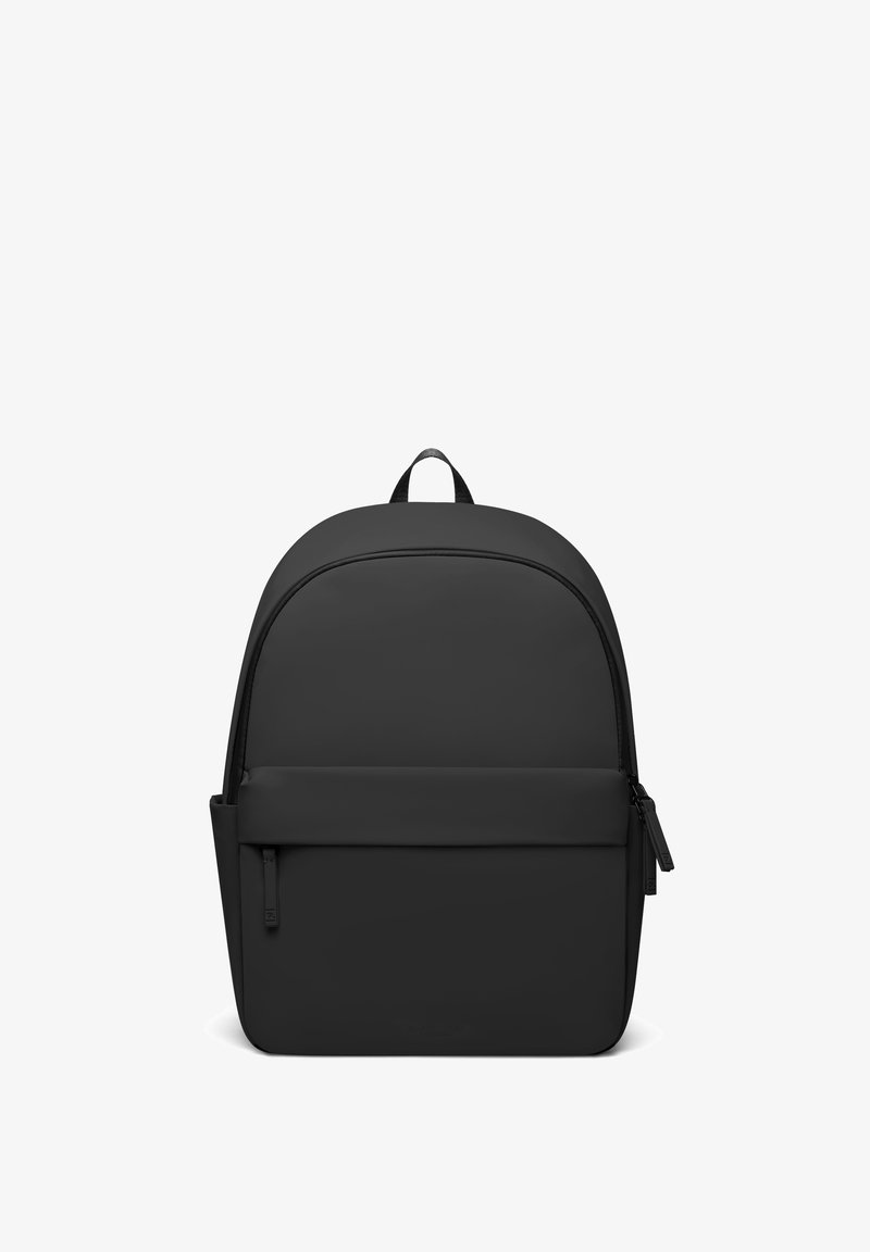 Sac à dos noir minimaliste avec un grand compartiment principal, une poche avant zippée, une poche latérale et une poignée sur le dessus, présenté sur un fond blanc.