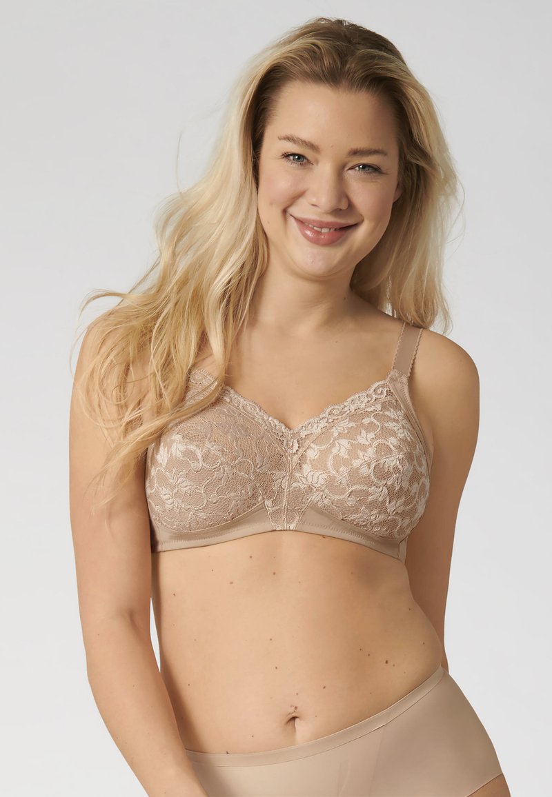 Reggiseno con sovrapposizione in pizzo e colore beige chiaro, dotato di spalline regolabili e design senza cuciture. Texture liscia con dettagli a motivo floreale.