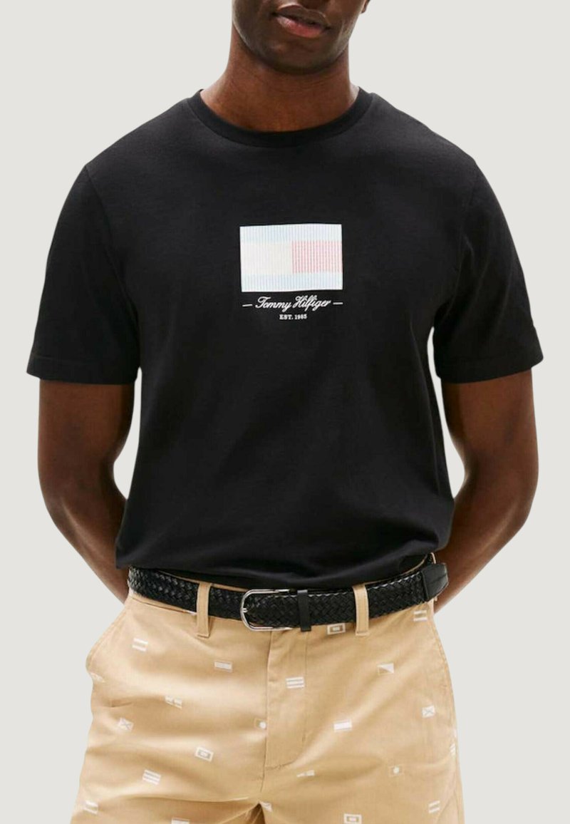 Czarna bawełniana koszulka z prostokątnym wzorem logo w jasnoniebieskim i czerwonym kolorze, z napisem "Tommy Hilfiger" oraz "EST. 1985" poniżej.