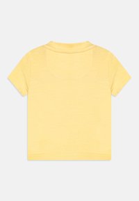 Žluté bavlněné tričko s krátkým rukávem, kulatým výstřihem a viditelnými švy. Hladký povrch a minimalistický design.