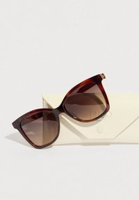 Sötét teknősbéka mintájú cicás napszemüveg, barna átmenetes lencsékkel. Tartozik hozzá egy világos színű, geometriai mintájú kemény tok.