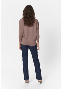 Hnědý pletený top s třičtvrtinovými rukávy, v kombinaci s tmavě modrými rozšířenými džínami. Oba kusy mají volný střih a minimální detaily.