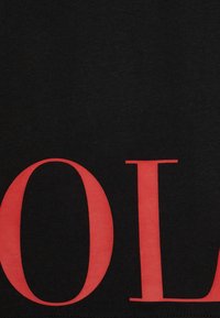 Svart tyg med stora röda seriferade bokstäver "OL" tryckta på det.