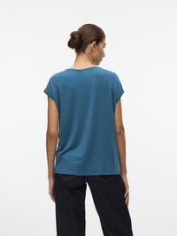 Tricou cu mânecă scurtă, de culoare albastră, cu o croială lejeră, textură fină, decolteu rotund și tiv drept, purtat cu pantaloni de blug închis.
