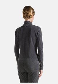 Zwarte fleece top met lange mouwen en een opstaande kraag; zachte textuur en een strak ontwerp; label zichtbaar aan de achterkant nabij de halslijn.