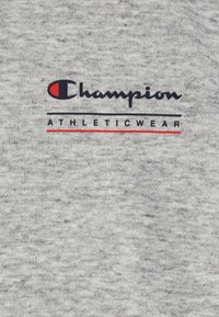 Pelēkas treniņjakas audums ar hetera tekstūru. Izceļas ar melnu "Champion" logotipu ar sarkanu akcentu un melnu uzrakstu "ATHLETICWEAR" zem tā.