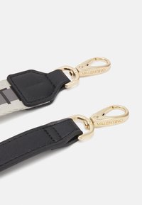 Černý a šedý popruh se zlatými kovovými klipy, s texturovanými detaily a logem na jednom klipu; hladký povrch s odolným designem.