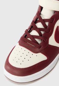 Baskets montantes en cuir bordeaux avec des accents crème, languette en mesh texturé et boîte à orteils perforée. Lacets de couleur bordeaux assortie.