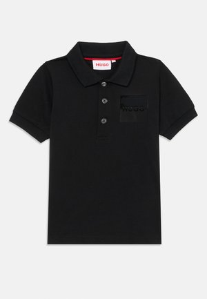Polo noir en coton avec un col, trois boutons et une patch logo texturé noir sur la poche poitrine. Design simple.