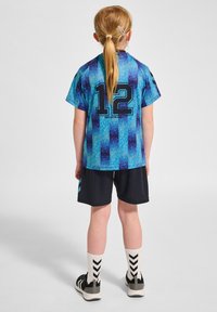 Blå och svart sportoutfit med en texturerad tröja som har en iögonfallande ryggdesign med nummer "12", tillsammans med enfärgade svarta shorts och randiga strumpor.
