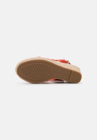 Sandalo espadrilles rosso con suola in juta intrecciata, suola in gomma e cinturino regolabile con fibbia. Presenta motivi testurizzati sul fondo.
