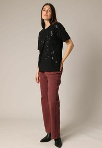 Black short-sleeve t-shirt with textured embellishments; paired with maroon high-waisted pants and sleek black ankle boots.