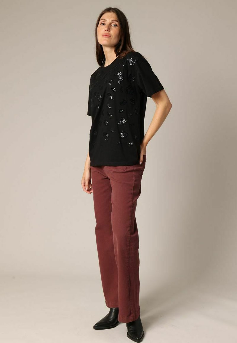Black short-sleeve t-shirt with textured embellishments; paired with maroon high-waisted pants and sleek black ankle boots.