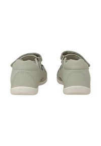 Scarpe slip-on verde chiaro con una superficie in pelle liscia, suole in gomma bianca e dettagli ritagliati sui lati. Tacco rotondo e parte posteriore.