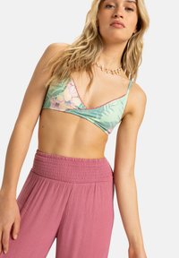 Bralet s cvetnim vzorcem v mint zeleni barvi z tankimi naramnicami, v kombinaciji z visoko pasom, teksturiranimi roza hlačami z nabranim pasom.