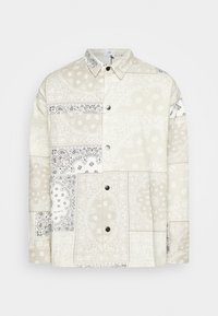 Camicia patchwork crema e beige con motivi paisley, chiusura a bottoni e colletto appuntito. Tessuto morbido con un aspetto testurizzato.