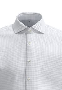 Witte overhemd met een klein blauw en marineblauw stippenpatroon. Voorzien van een button-down kraag en vijf knopen aan de voorkant. Gemaakt van katoen.