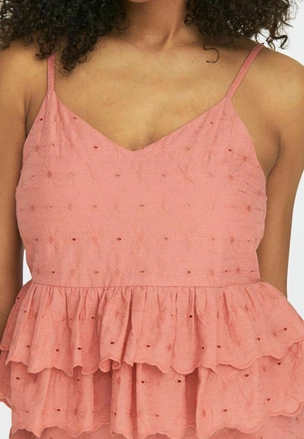 Top sin mangas de color durazno con escote en forma de V, bajo de capas con volantes y patrones florales bordados en toda la tela.
