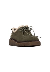 Zapatos de ante verde con cordones y un cuello de piel sintética color crema, suela gruesa marrón y puntera redonda. Presentan ojales simples y acentos mínimos.