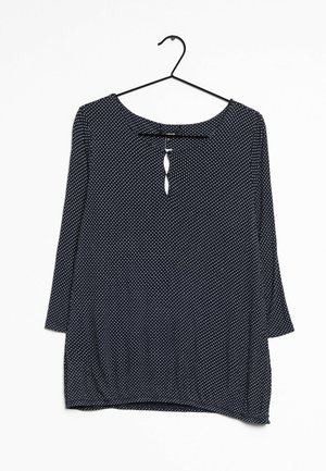 Top blu navy con pois bianchi, scollatura rotonda, dettaglio a chiave nella parte anteriore e maniche a tre quarti. Realizzato in tessuto leggero.