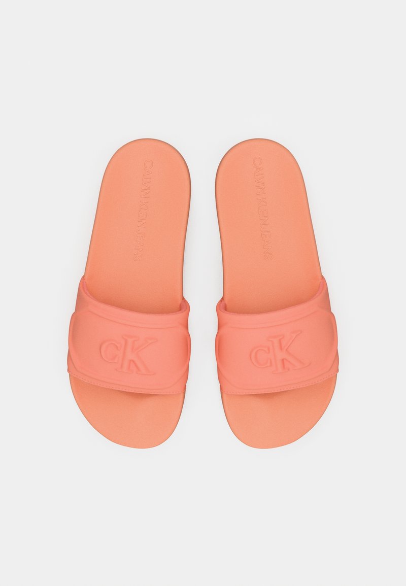 Chanclas naranjas con una correa texturizada y el logo "ck" en relieve. Plantilla suave y diseño de punta abierta y redondeada.