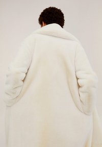 Crème faux fur jas met een brede kraag en oversized mouwen, met een gladde, gestructureerde afwerking en grote zijzakken.