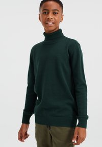 Temnozeleni pulover s turtleneck iz mehkega pletenega materiala, z rebrastimi manšetami in robom. Zasnovan za sproščen kroj.