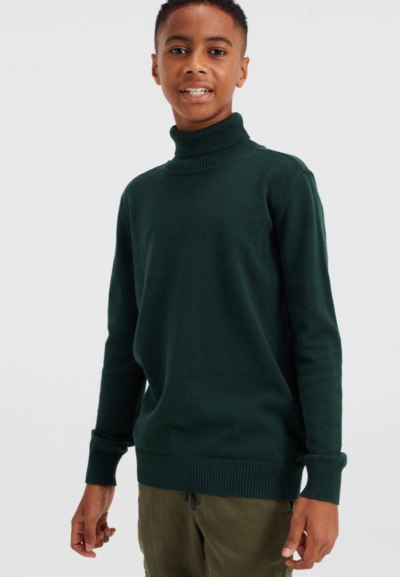Temnozeleni pulover s turtleneck iz mehkega pletenega materiala, z rebrastimi manšetami in robom. Zasnovan za sproščen kroj.