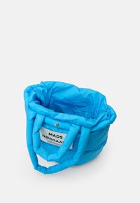 Saco tote azul acolchoado com duas alças, apresentando um rótulo branco com "MADS NØRGAARD COPENHAGEN". Superfície texturizada, forma redonda, material suave.