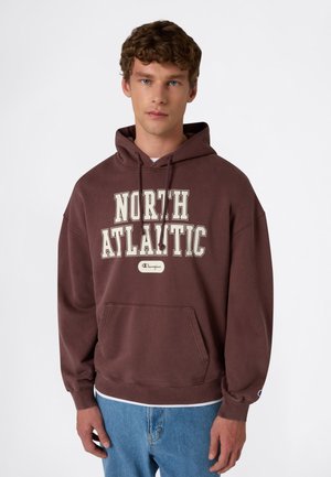 Felpa marrone con cappuccio, tasca frontale, coulisse e testo stampato "NORTH ATLANTIC". Presenta il logo Champion nella parte inferiore anteriore e sulla manica.