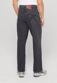 Tummanharmaat farkut suoranmallisella mitoituksella, nahkainen logo-patch vyötäröllä ja brodeerattu "R"-yksityiskohta takataskuissa.