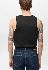 Zwarte mouwloze shirt van ribmateriaal, gezien vanuit de achterkant, gecombineerd met blauwe spijkerbroeken met een klassiek zakontwerp.