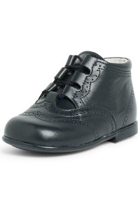 Stivale alla caviglia in pelle nera con perforazioni decorative e cinque lacci. Punta arrotondata e suola piatta con una texture liscia.