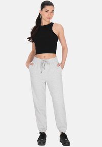 Sort cropped tanktop parret med lysegrå sweatpants. Sweatpants har en elastisk talje og sidelommer. Sorte sneakers fuldender outfittet.